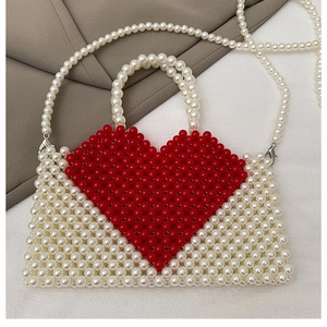 Detail of handmade beaded tote with white pearls and red heart pattern close-up
