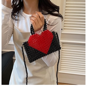 Detail of handmade beaded handbag featuring a red and black heart pattern with crossbody strap