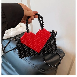 Detailed close-up of handmade beaded mini handbag with red heart pattern and cross-body chain