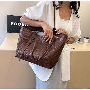 Close-up of a large dark brown woven tote bag featuring a high-quality leather texture