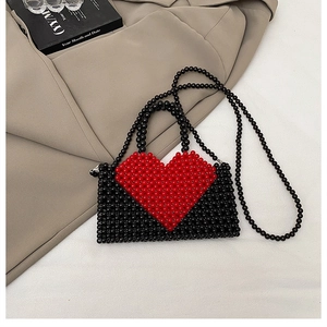 Close-up of handmade black beaded bag featuring a red heart pattern and dual straps