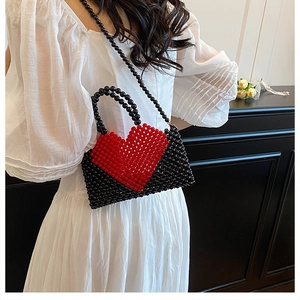 Handmade black beaded handbag with a red heart pattern shown on a white dress