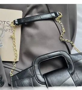 Detail of black crocodile embossed leather handbag with golden chain strap and top handle