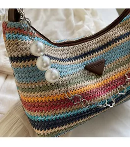 Detail of colorful striped woven beach bag with pearl charm and silver petal chain