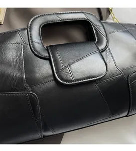 Detail of black leather handbag featuring geometric stitching and gold chain strap