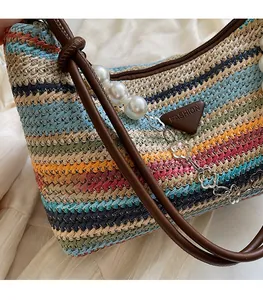Detail of colorful woven beach bag with pearl chain strap and metal floral pendant
