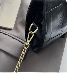 Close-up of premium gold-tone hardware and glossy black leather texture on the handbag
