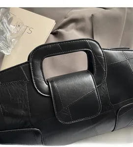 Detail of black geometric leather handbag featuring an integrated rectangular handle