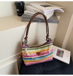 Detail view of woven beach tote with colorful stripes, pearl chain, and leather handles