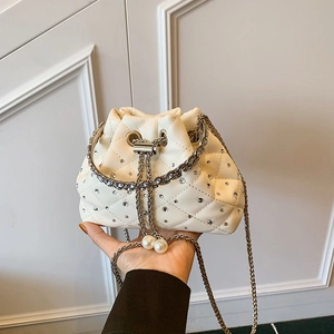 Chic cream quilted bucket bag with rhinestones, silver chain strap, and pearl drawstring