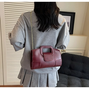 Detail of burgundy quilted leather handbag with gold chain strap shown on model shoulder