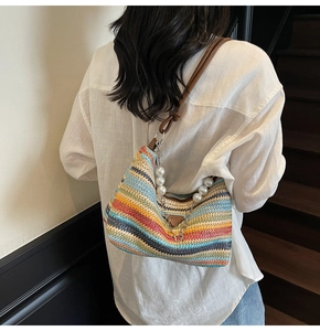 Detail of colorful striped woven beach bag with pearl handle chain and leather shoulder strap
