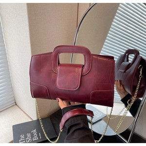 Detail of burgundy leather handbag featuring unique patchwork stitching and gold chain strap
