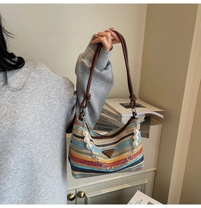 Detail of colorful striped straw shoulder bag with leather strap and pearl chain charm