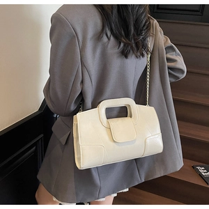Detail of cream chain bag with geometric stitching and elegant gold chain strap