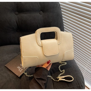 Detail of cream leather handbag with geometric stitching and gold chain strap