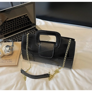 Detail of black patchwork handbag featuring a geometric stitching and gold chain strap