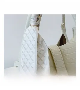 Detail of cream basket bag showing crocodile embossed texture and silk scarf handle decor