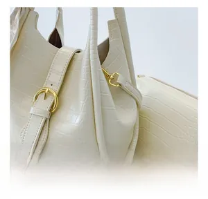 Close-up of white crocodile pattern leather texture and golden metal buckle on tote bag