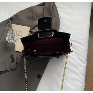 Interior view of black leather handbag with burgundy lining and gold chain strap
