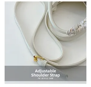 Detail of adjustable white crocodile embossed leather strap with gold metal buckle