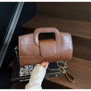 Close-up of brown textured leather handbag with geometric stitching and gold chain