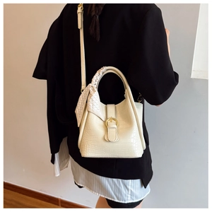 Detail of cream white faux crocodile handbag with silk scarf and gold buckle