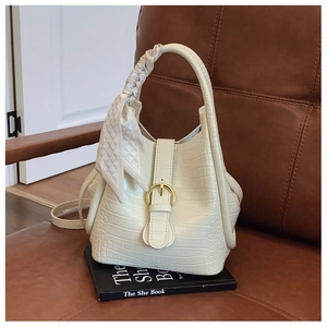 Detailed view of white crocodile pattern handbag with elegant scarf-wrapped handle