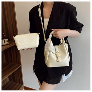 Detail view of cream crocodile textured bucket bag set with decorative scarf and gold clasp