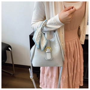 Close-up of blue crocodile pattern bucket bag with decorative scarf and gold hardware