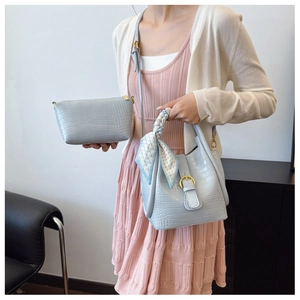 Detail of light blue crocodile embossed bucket bag set with scarf handle and gold hardware