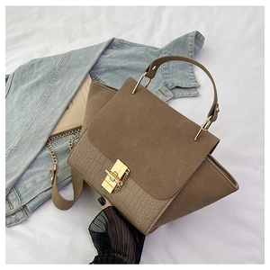 Brown crocodile pattern crossbody bag with gold chain strap and square lock on silk background