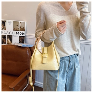 Detail of yellow crocodile embossed bucket bag with silk scarf handle and long shoulder strap
