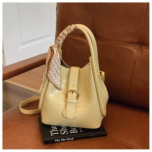 Detail of yellow crocodile pattern bucket bag with decorative silk scarf and gold hardware