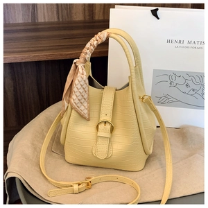Detail of yellow crocodile pattern bucket bag with silk scarf handle and gold buckle