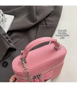 Detail of pink lychee leather handbag with rounded handle and silver chain strap