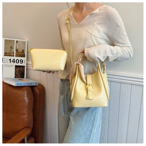 Detailed view of yellow crocodile-patterned bucket bag and inner pouch set on a sofa