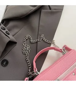 Detailed macro view of pink lychee textured leather bag with silver metal chain and zipper