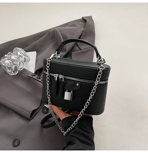 Detail of black pebbled leather box bag with silver hardware and chain strap