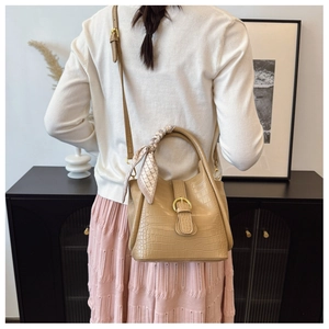 Close-up of brown crocodile texture bucket bag with decorative silk scarf and gold clasp
