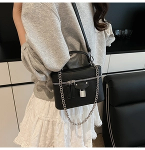 Detail of black lychee grain box bag with silver padlock and chain shown on model