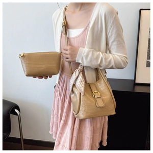 Detail of khaki bucket bag with faux crocodile texture and geometric silk scarf accent