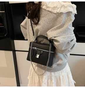 Detail of black pebbled leather vanity box bag with silver hardware on a model