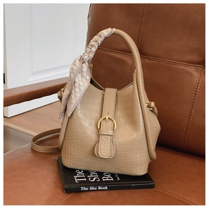 Macro detail of khaki crocodile texture handbag with silk scarf and gold buckle