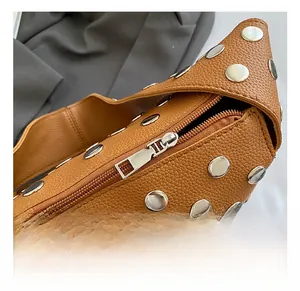 Detailed close-up of brown litchi grain leather bag with silver metal studs and zipper
