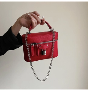 Detail of red litchi leather box bag with silver padlock and chain strap