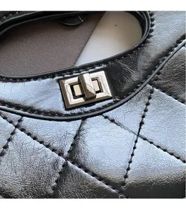 Close-up of black quilted leather handbag with metallic turn-lock closure and stitching
