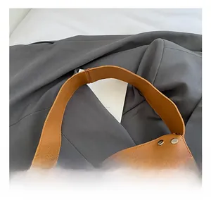 Detail of brown litchi leather shoulder bag with silver studs and wide strap handle