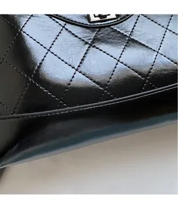 Macro shot of black quilted faux leather fabric with metallic clasp detail on shoulder bag