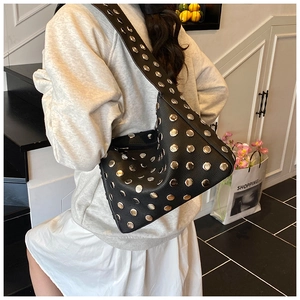 Detail of black pebbled leather tote bag with silver studs and wide shoulder strap